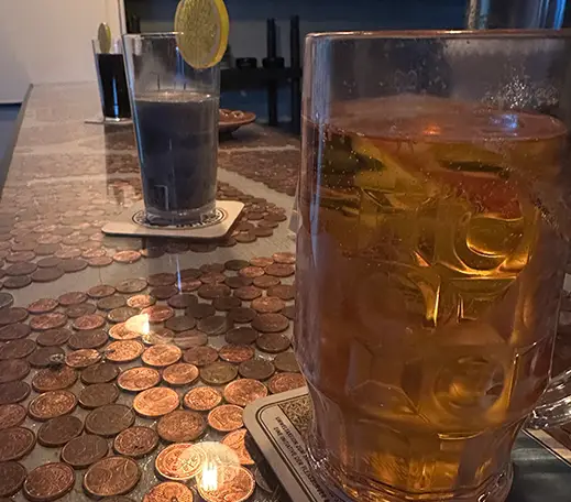 mystery_pub_02 Auf dem Bild ist ein Ausschnitt eines Tresens zu sehen. Auf dem Tresen stehen 3 Getränke auf einem Untersetzer.