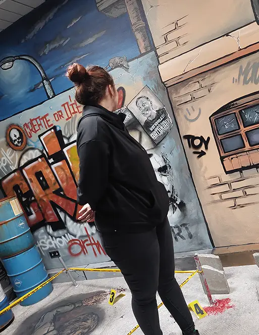 tatort_flensburg_01 Eine Frau steht in einem Raum, der mit Graffiti besprüht ist. Sie dreht sich mit den Kopf nach hinten.